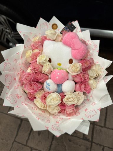 A bouquet of pink roses with a Hello Kitty plush toy in the center.