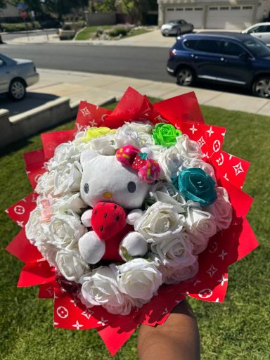 A bouquet featuring a Hello Kitty plush surrounded by white flowers and colorful accents.