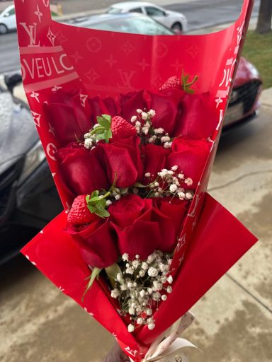 A bouquet of red roses with baby's breath in a decorative wrap.