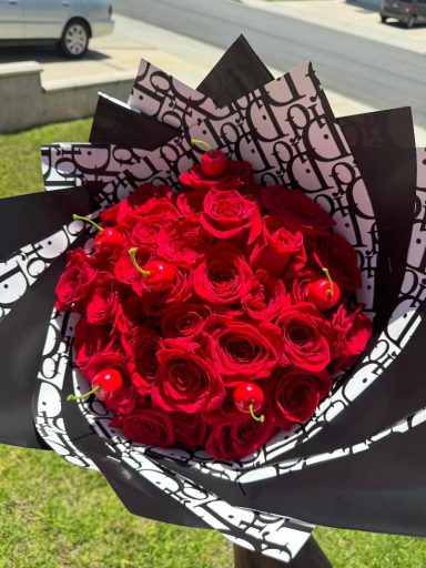 Bouquet of red roses wrapped in black and white patterned paper.