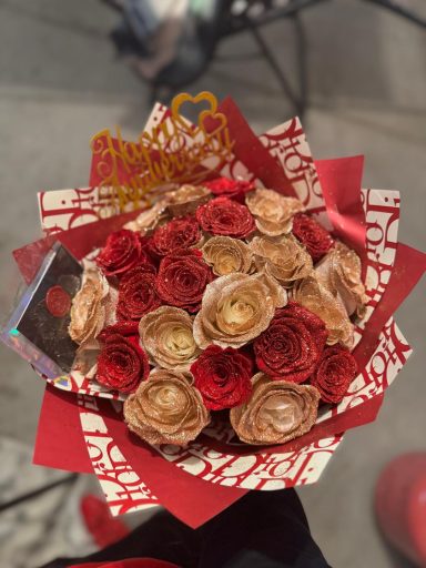 A bouquet of red and cream roses wrapped in decorative paper.